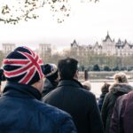 Erwachsene in London stehen in Gruppe vor der Themse