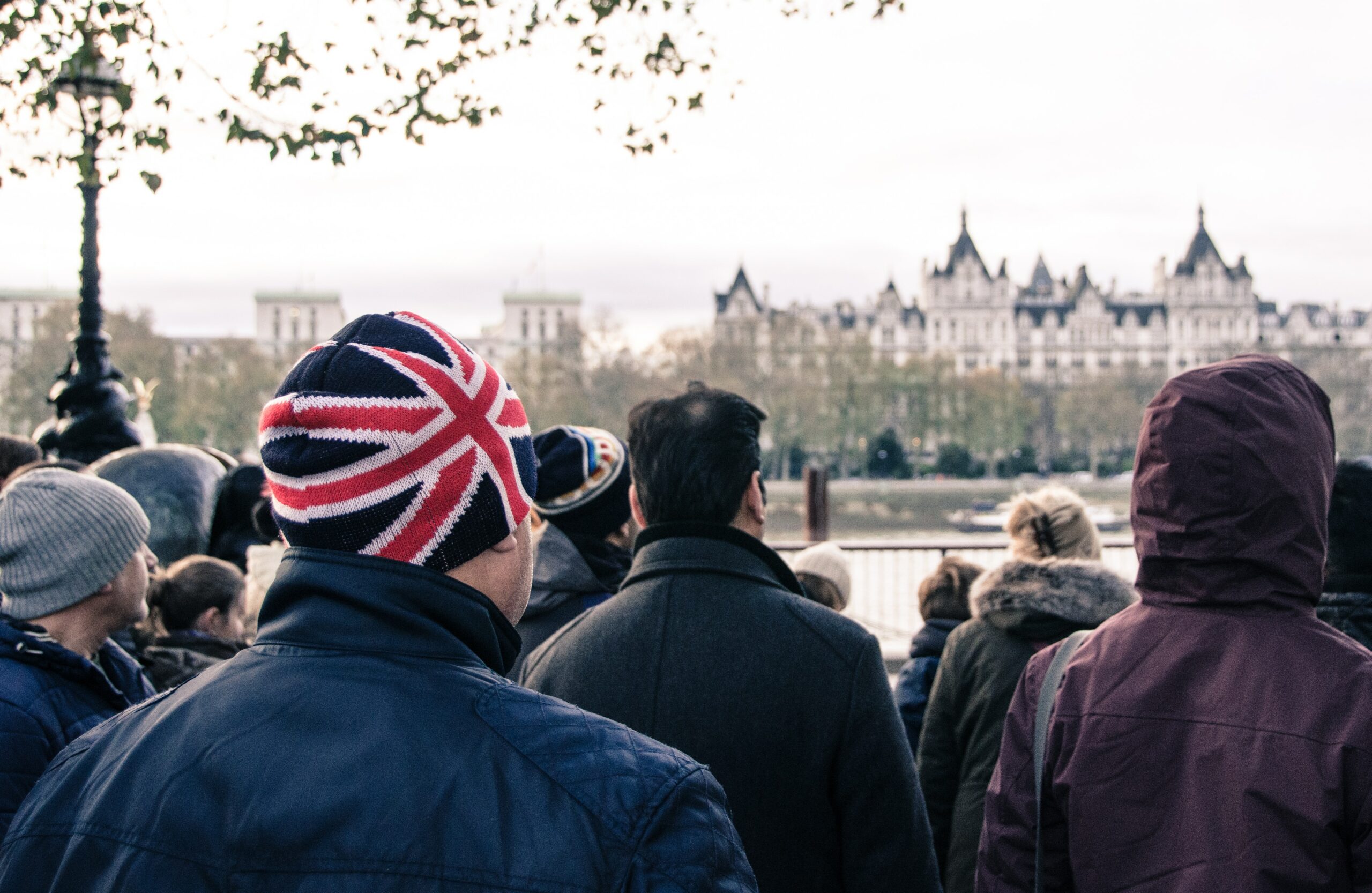 Erwachsene in London stehen in Gruppe vor der Themse