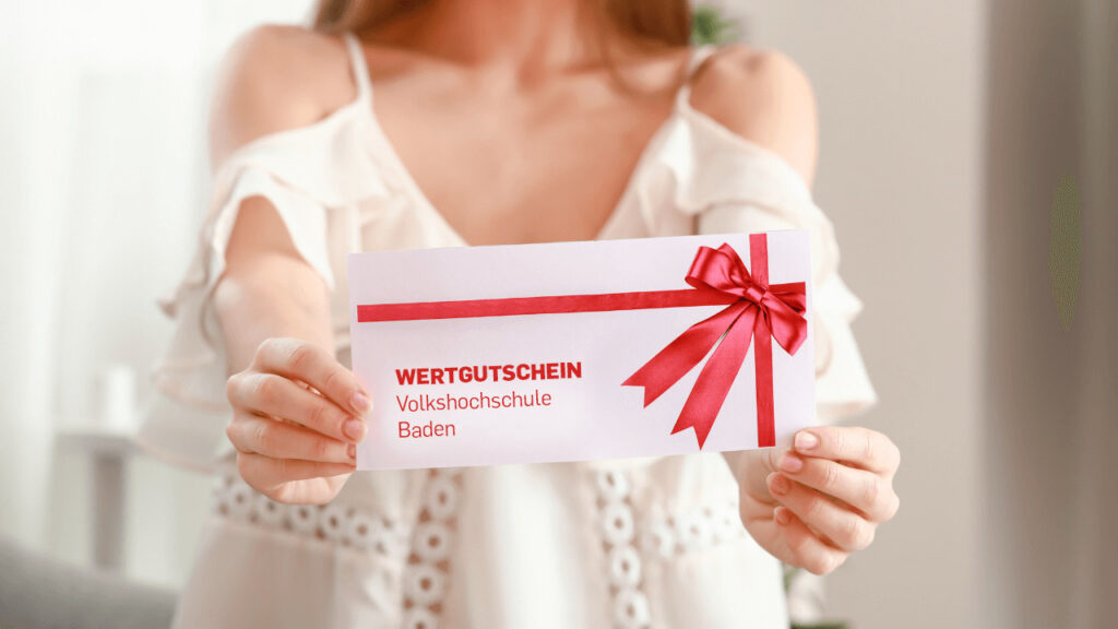 Frau hält Wertgutschein der Volkshochschule Baden in die Kamera