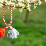 Ein rot-weißes Wollband hängt an einem blühenden Ast in Ungarn
