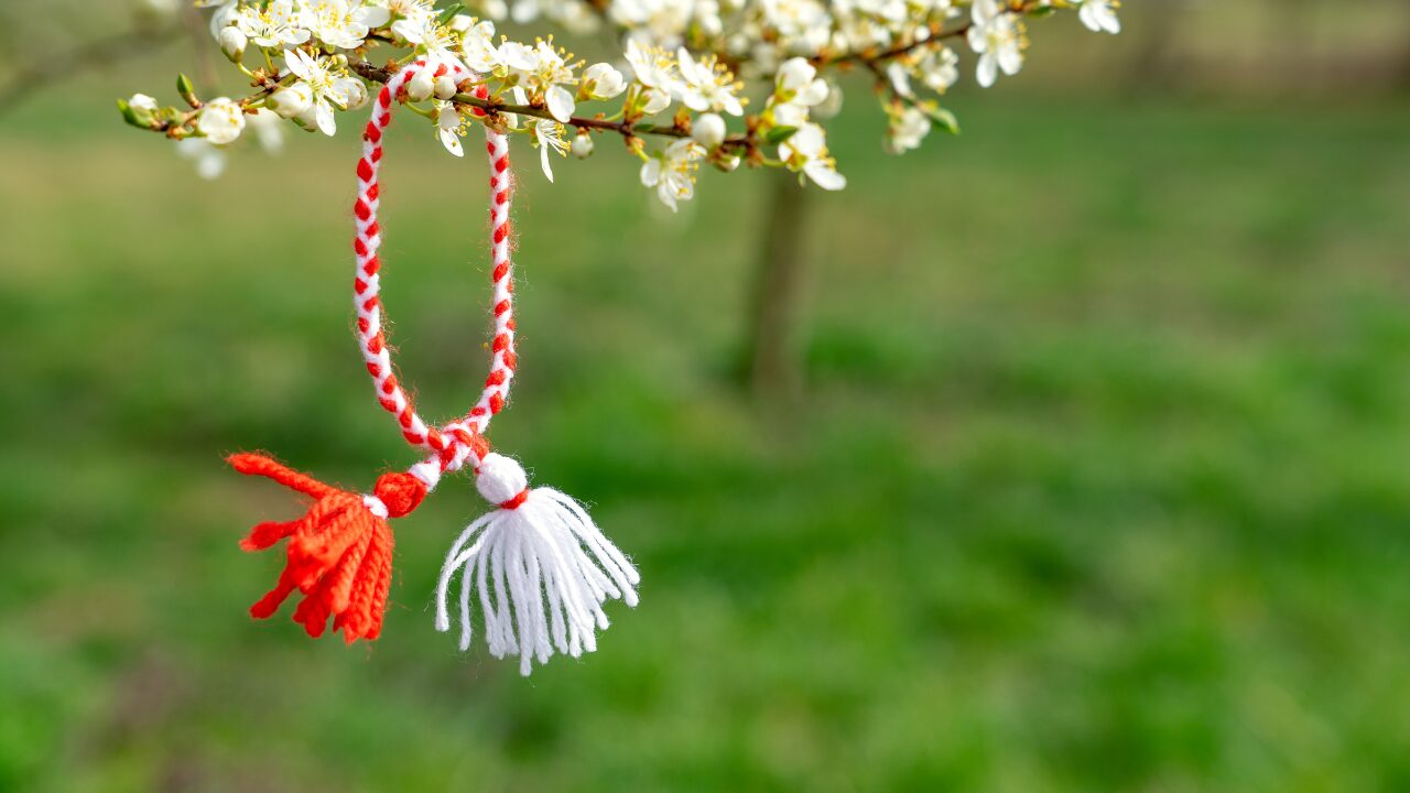 Ein rot-weißes Wollband hängt an einem blühenden Ast in Ungarn