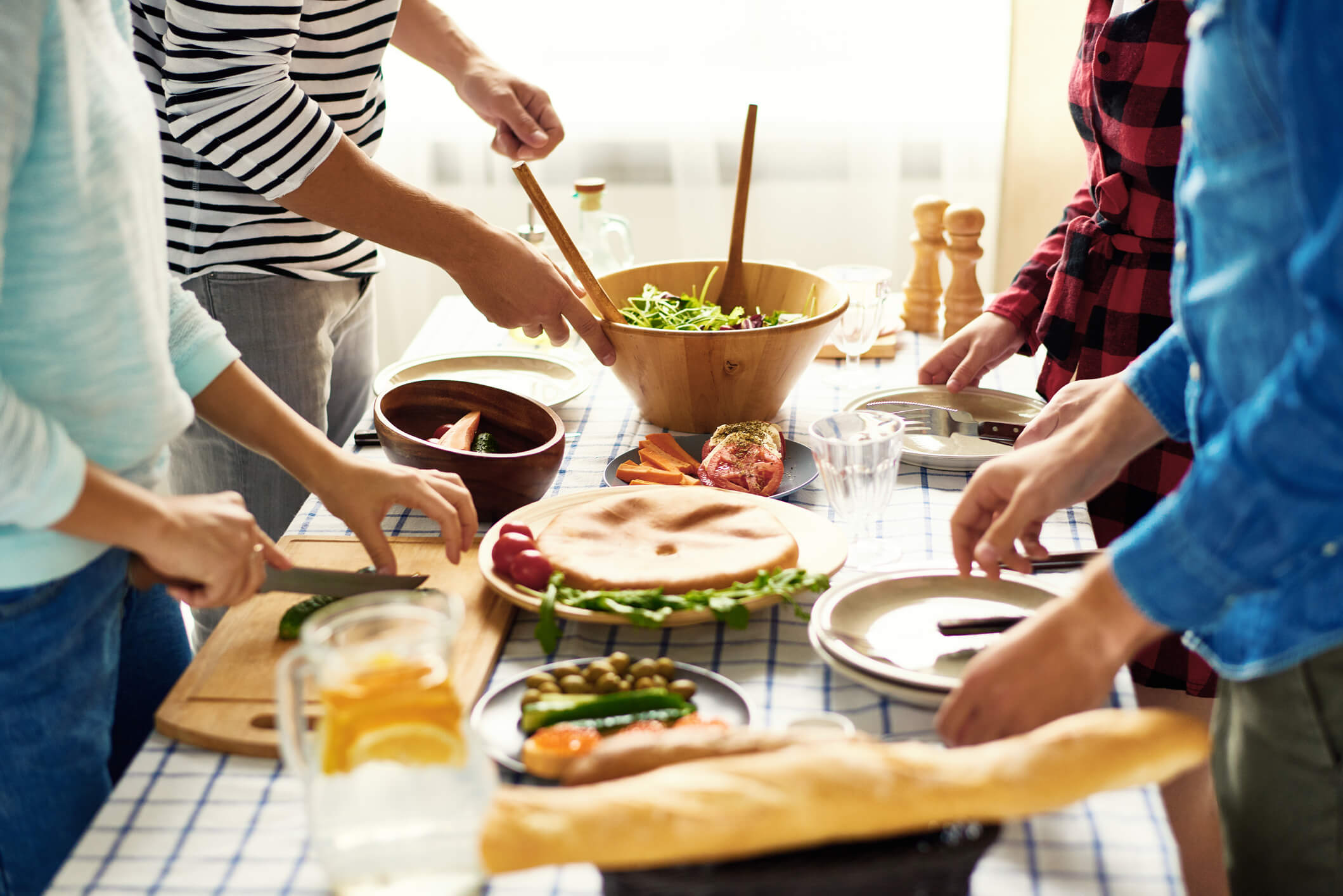 Menschen kochen gemeinsam an großem Tisch im Kochkurs an der VHS
